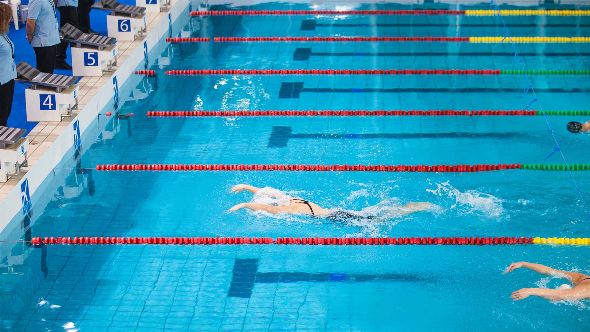 An olympic sized swimming pool with a swimmer in it