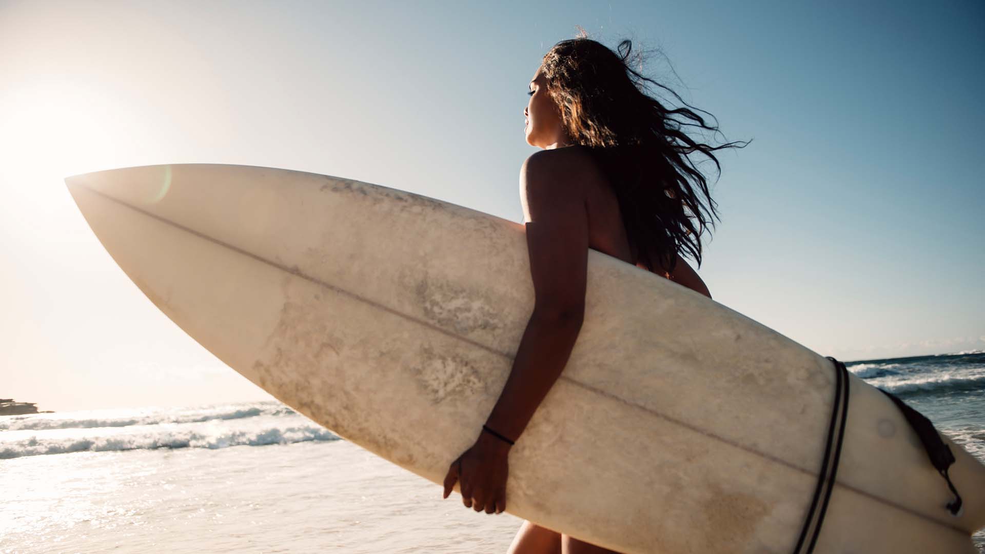 A woman holding a surfboard at the beach